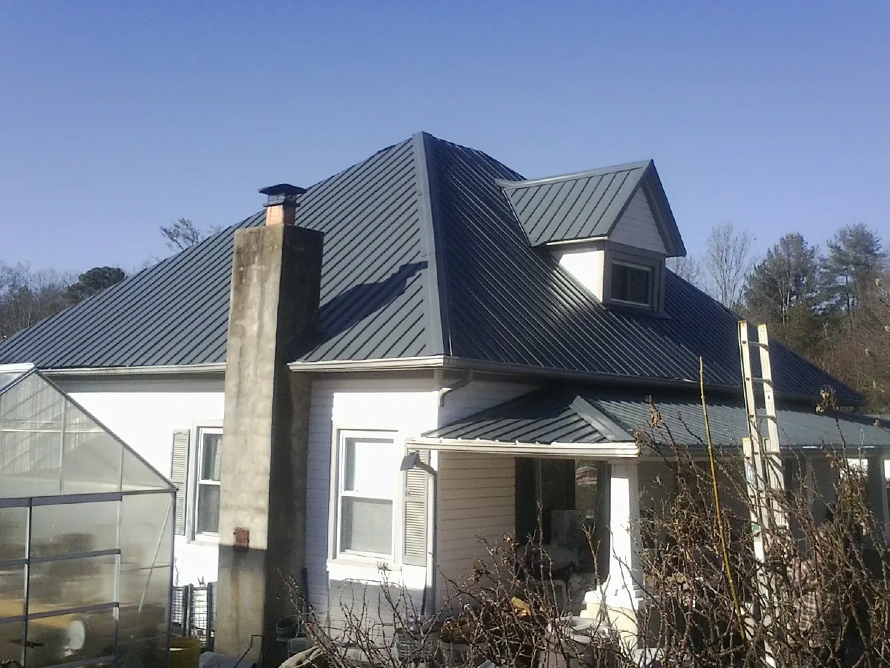 Dark blue standing seam metal roof on a white farmhouse with dormer — Slate & Tile Roof Repair by Roofing Brothers in Asbury Park
