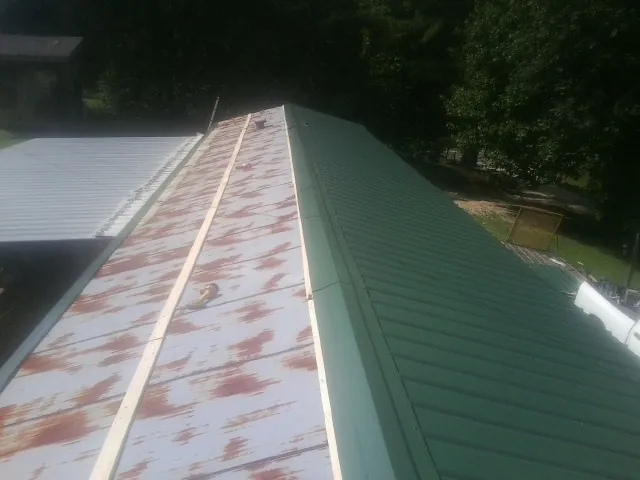 Old rusted panels beside newly installed green metal roofing — Wind Damage Roof Repair by Roofing Brothers in Asbury Park