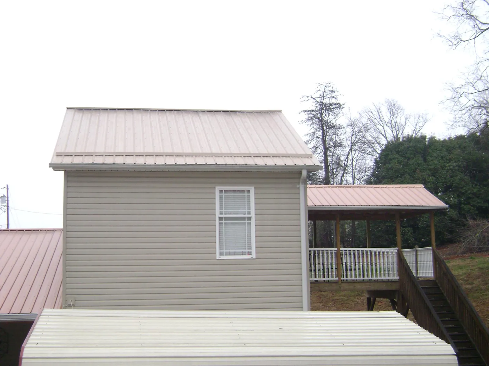 Tan metal roofs on a two story addition and attached porch, from a Roof Replacement job in Asbury Park