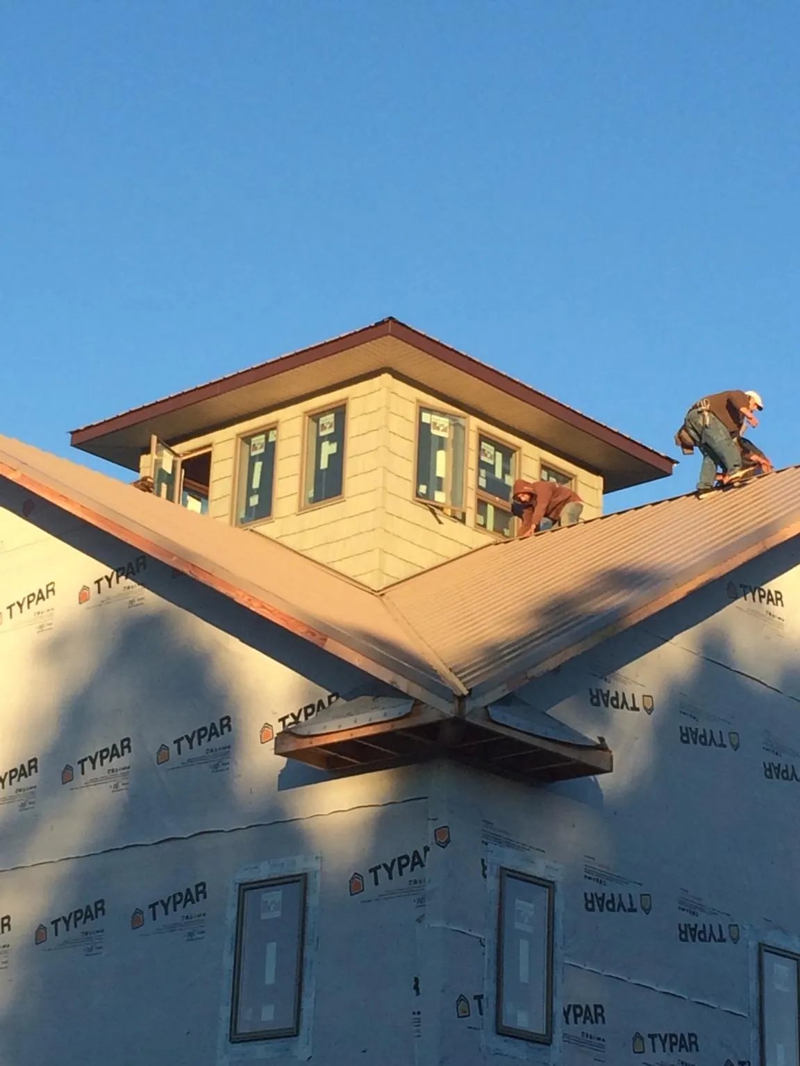 Roofers working around a rooftop cupola on a new metal roof at sunset — Roof Waterproofing in Asbury Park by Roofing Brothers